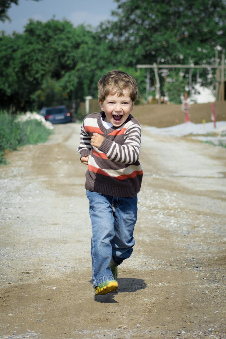 A young boy joyfully runs down a path, showcasing playful energy in a Czech outdoor setting.