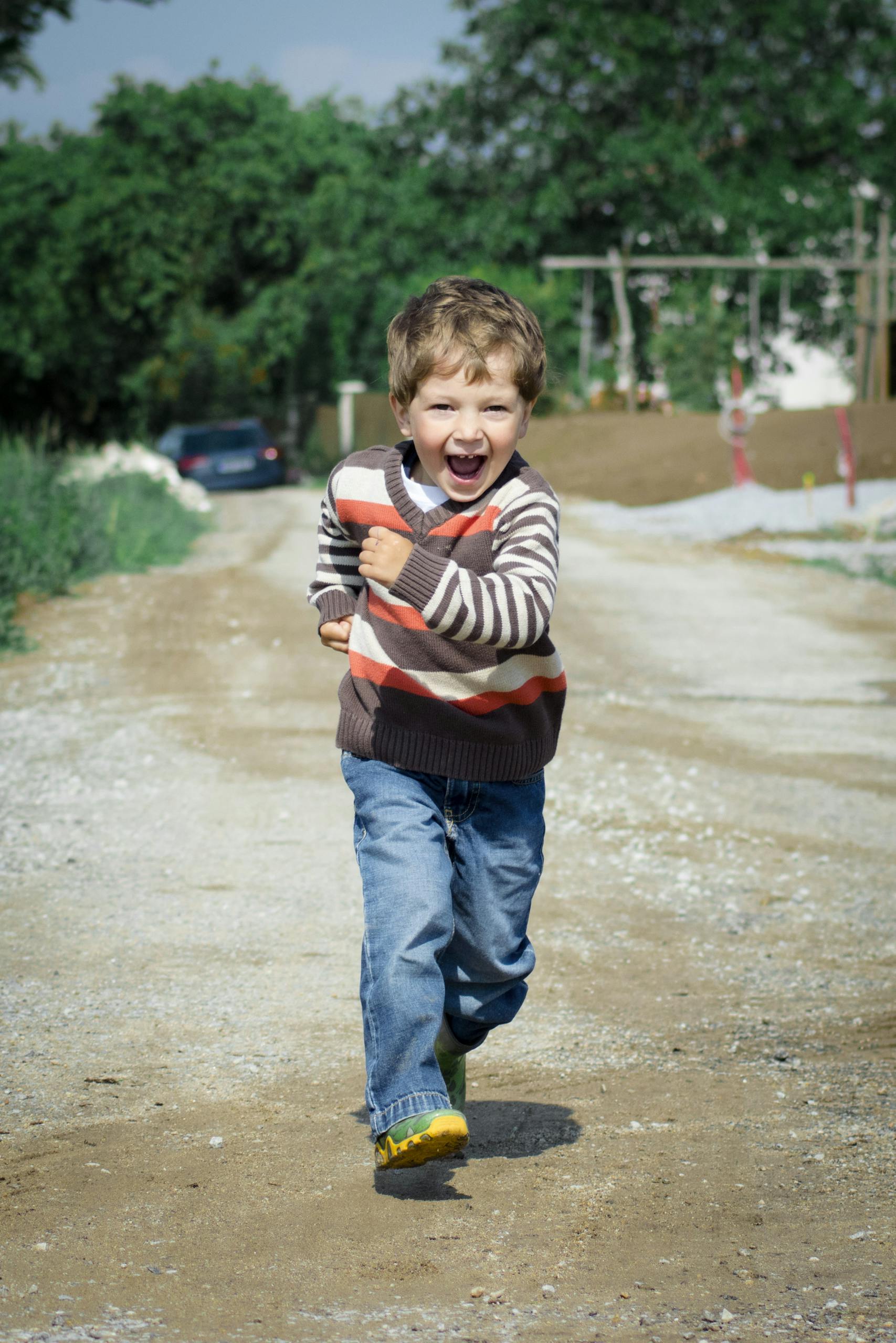 A young boy joyfully runs down a path, showcasing playful energy in a Czech outdoor setting.